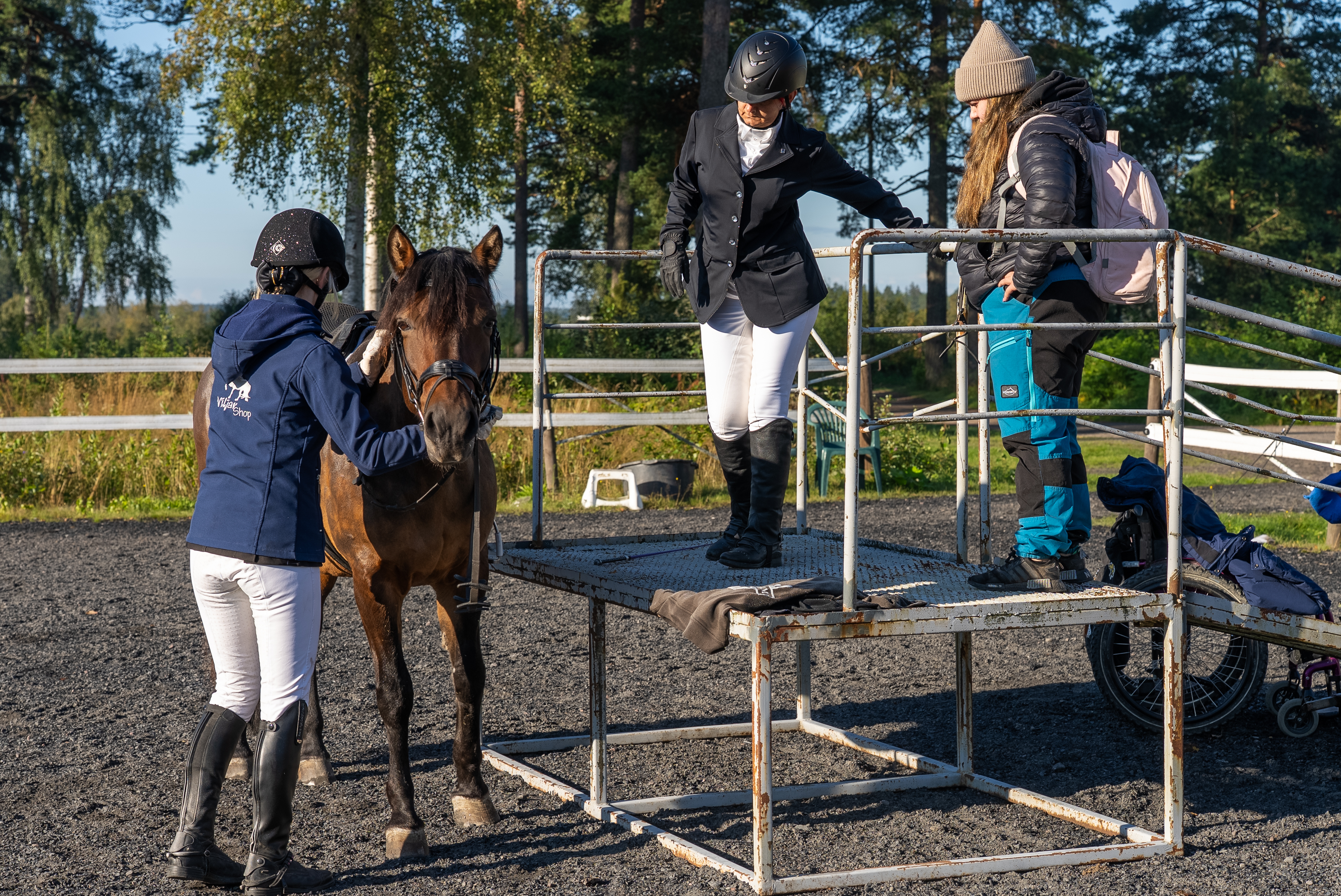 Kuvassa henkilö nousemassa hevosen selkään nousukorokkeelta.